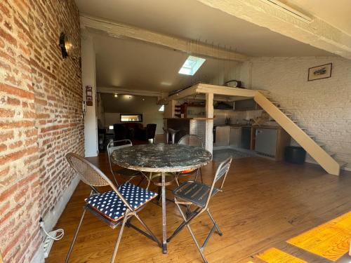- une table et des chaises dans une pièce dotée d'un mur en briques dans l'établissement Loft de charme climatisé et sa terrasse, à Toulouse