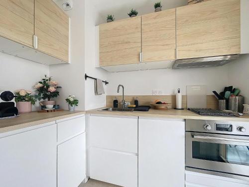 - une cuisine blanche avec des placards en bois et un évier dans l'établissement Blue sky-Plage 2min-Plein Sud, au Golfe-Juan