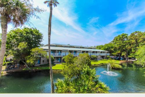 a hotel with a pond and palm trees and a building at Players Club Resort in Hilton Head Island