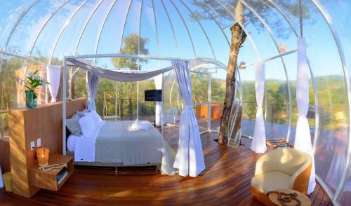 ein Schlafzimmer mit Himmelbett in einem Glashaus in der Unterkunft Villa das Cabanas – Viva o Luxo da Natureza em Piri in Pirenópolis