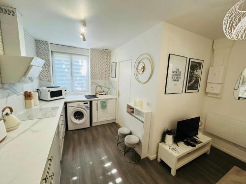 une cuisine avec des placards blancs et un ordinateur sur une table dans l'établissement CosyBulles Centre-ville Tramway, à Reims