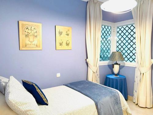 Un dormitorio azul con una cama y una ventana. en Espectacular piso en primera línea de playa, en Estepona