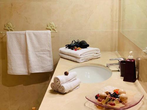 Un baño con un lavabo con toallas y un plato de comida. en Espectacular piso en primera línea de playa, en Estepona