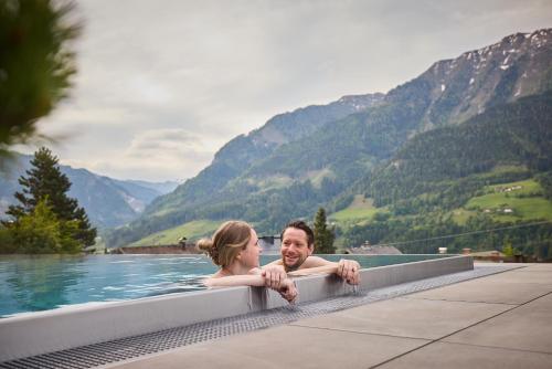 a man and a woman in a pool in the mountains at Designhotel Sonnhof by Vitus Winkler in Sankt Veit im Pongau