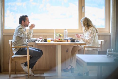 a man and woman sitting at a table eating food at Designhotel Sonnhof by Vitus Winkler in Sankt Veit im Pongau
