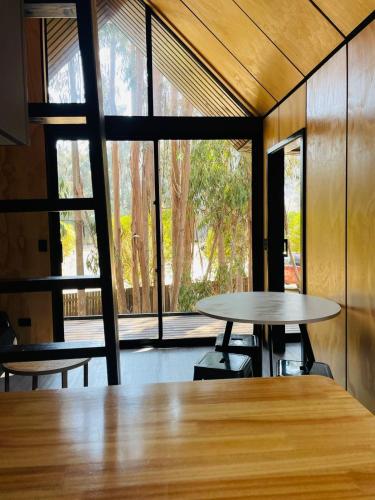 a room with two tables and a large window at Parque Laguna de Zapallar in Maitencillo