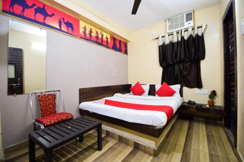 a bedroom with a bed with red pillows and a chair at Hotel O Kota Airport Formerly Vaishnavi in Kota