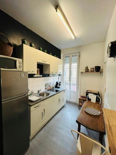 une cuisine avec un réfrigérateur en acier inoxydable et une table dans l'établissement Le Prestigieux Ruinart - Centre-Ville, à Reims