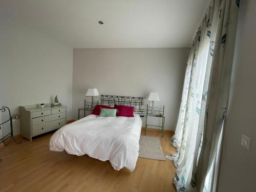 a bedroom with a bed with white sheets and red pillows at Calle Oceano atlantico 66 in El Puerto de Santa María