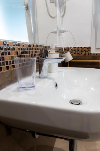 a white sink in a bathroom with a glass at La dimora dei ricci in Santo Stefano di Camastra