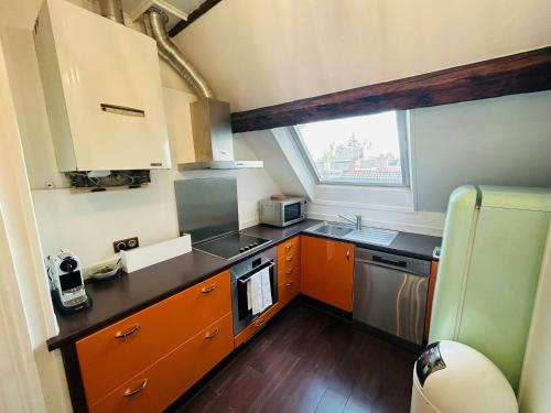 une petite cuisine avec des armoires orange et une fenêtre dans l'établissement Le Majestueux Brulée Hypercentre Parking, à Reims