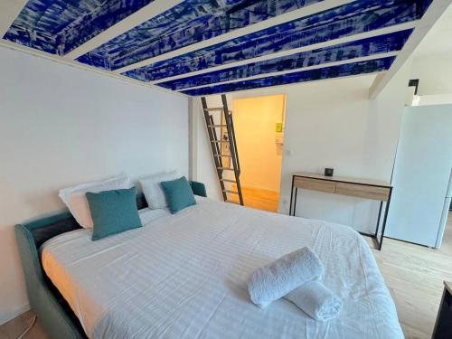 une chambre avec un grand lit blanc avec des oreillers bleus dans l'établissement Appartement élégant plage à 100m prom des anglais, à Nice