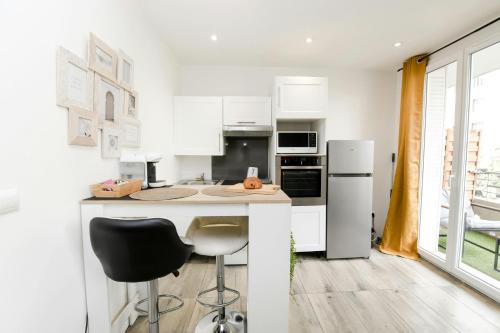 une cuisine blanche avec un comptoir et une chaise noire dans l'établissement Studio Cosy Business - Balcon Garage Fermé, à Lyon