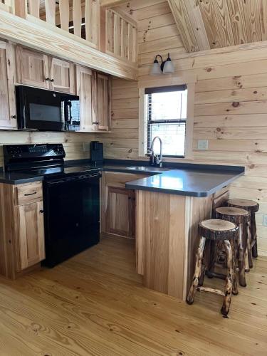 a kitchen with a black island in a log cabin at Tiny Cabin #4 by Windham NY Escape 'Cabin Comfort' in Hensonville