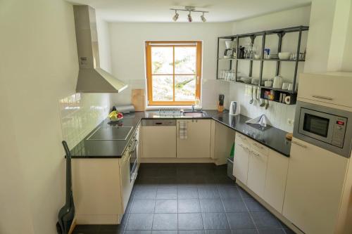 a kitchen with white cabinets and a window at Andrea 3 by SMR Luxury Apartments inc Spa and near Gondola in Rauris
