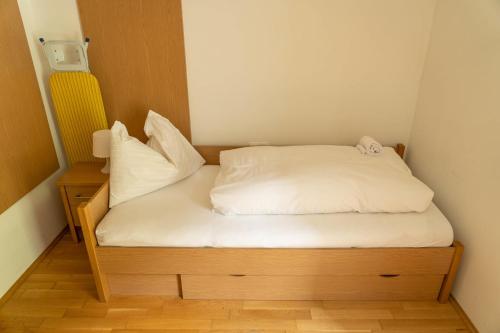 a small bed with white sheets and pillows in a room at Andrea 1 by SMR Rauris Apartments inc SPA and near Gondola in Rauris
