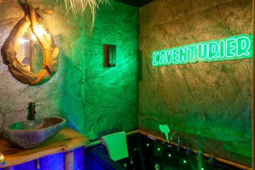 a green bathroom with a sink and a mirror at L'aventurier - Jacuzzi Lounge & Massage in Vierzon