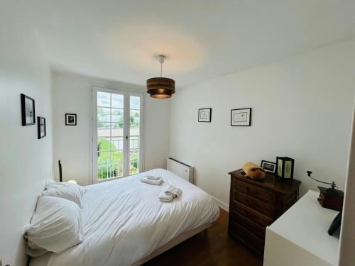 une chambre blanche avec un lit et une fenêtre dans l'établissement La Maison aux Oiseaux Calme, à Reims