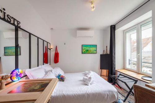 a bedroom with a bed and a desk and a window at Latelier DArtistes : expérience créative in Vierzon