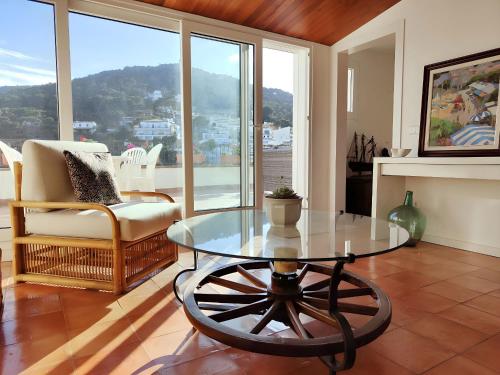 a living room with a glass table and a chair at Tamariu Platja · Penthouse on Passeig del Mar. in Tamariu