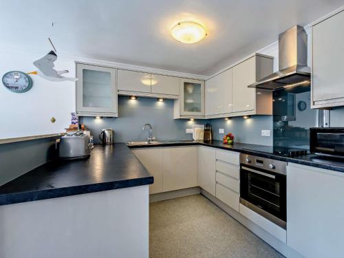 a kitchen with white cabinets and black counter tops at 2 bed in Woolacombe BKERS in Woolacombe