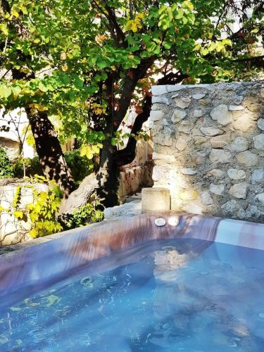une piscine avec une cascade et un mur en pierre dans l'établissement CASA-La Fontaine Maison Vacances Piscine, à Malaucène
