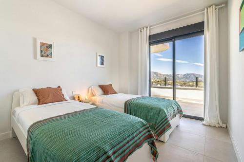 zwei Betten in einem Zimmer mit großem Fenster in der Unterkunft Bello piso con vistas espectaculares y un spa in Sitio de Calahonda