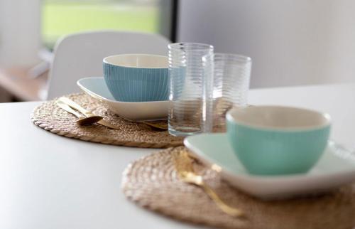 a table with three cups and plates and glasses at Le Havre du Daiquiri - Proche Paris in Aulnay-sous-Bois