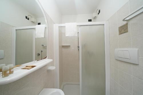 a white bathroom with a shower and a toilet at Hotel La Pergola in Moniga