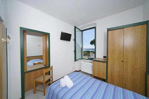 a bedroom with a bed and a dresser and a window at Hotel La Pergola in Moniga