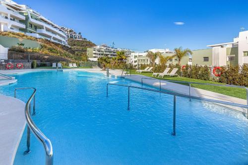 a large swimming pool with blue water and buildings at Bonito piso con Spa y vistas a la montaña in Sitio de Calahonda