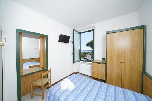 a bedroom with a bed and a chair and windows at Hotel La Pergola in Moniga