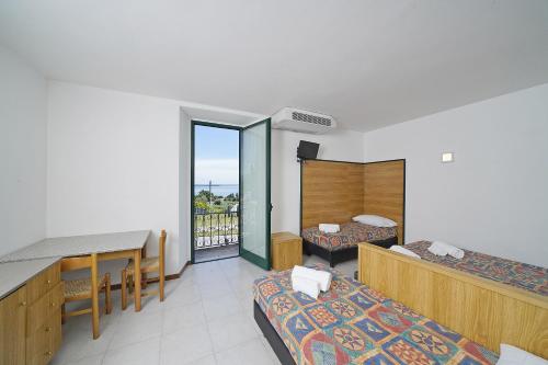 a hotel room with two beds and a balcony at Hotel La Pergola in Moniga