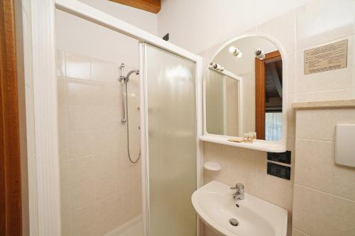 a white bathroom with a shower and a sink at Hotel La Pergola in Moniga
