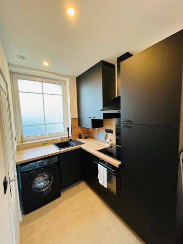 d'une cuisine équipée d'un réfrigérateur noir et d'une fenêtre. dans l'établissement La Suite Carteret Centre-ville, à Reims