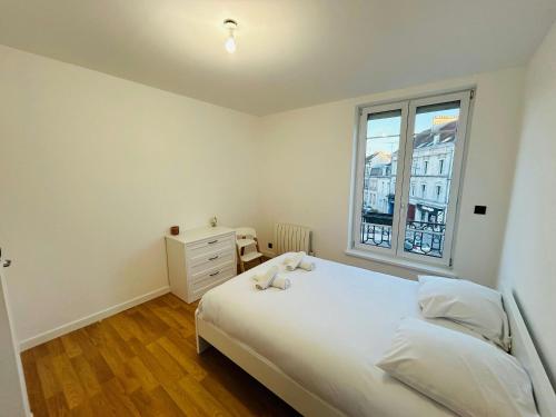 une chambre avec un grand lit blanc et une fenêtre dans l'établissement La Suite Carteret Centre-ville, à Reims