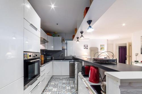 a kitchen with white cabinets and a black counter top at Citadin Cosy Nest Paris Area in Suresnes