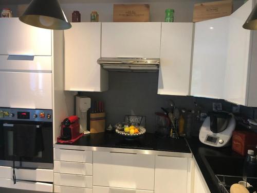 a kitchen with white cabinets and a bowl of fruit on the counter at Citadin Cosy Nest Paris Area in Suresnes