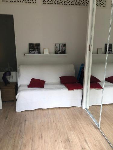 a bedroom with a bed with white sheets and red pillows at Citadin Cosy Nest Paris Area in Suresnes