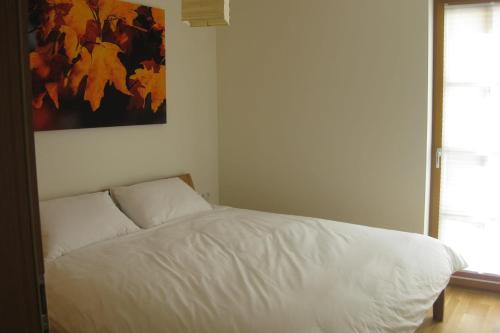 a white bed in a bedroom with a painting on the wall at Isabella 2 by SMR Rauris Apartments - inc Spa and near Gondola in Rauris