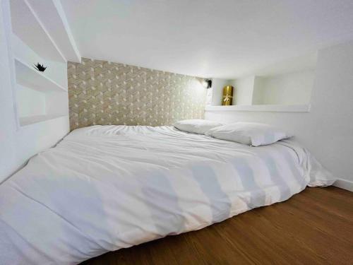 un lit avec des draps blancs et des oreillers dans une chambre dans l'établissement Le Champagne Coquebert Centre-ville, à Reims