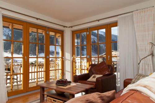 a living room with a couch and a table and windows at Johanna 3 by SMR Rauris Apartments - inc Spa and near Gondola in Rauris