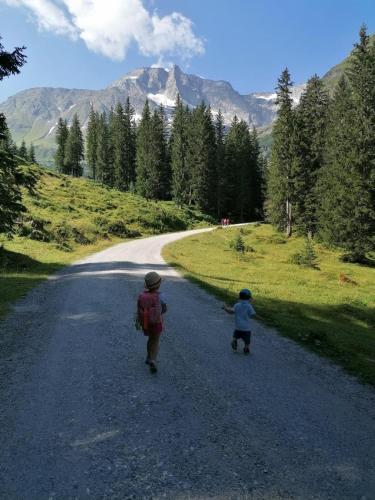 two children walking down a road with mountains in the background at Johanna 3 by SMR Rauris Apartments - inc Spa and near Gondola in Rauris