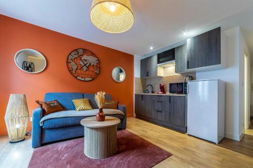 a living room with a blue couch and a kitchen at Appart'Hôtel - Le Sweet Terracotta in Fontainebleau