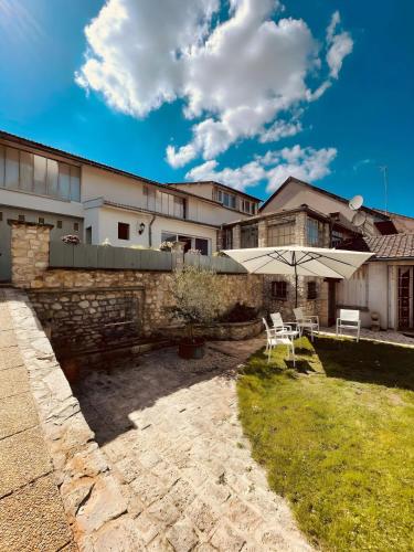 un patio avec une table et un parasol dans une cour dans l'établissement Magnifique Maison dartiste La Maison Aerts, à Reims