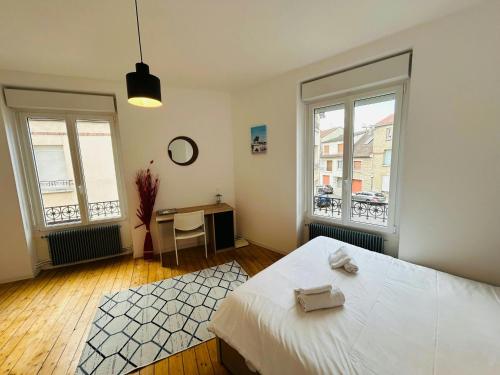 une chambre avec un lit et un bureau et deux fenêtres dans l'établissement Le Millésime Coulvier Taittinger, à Reims