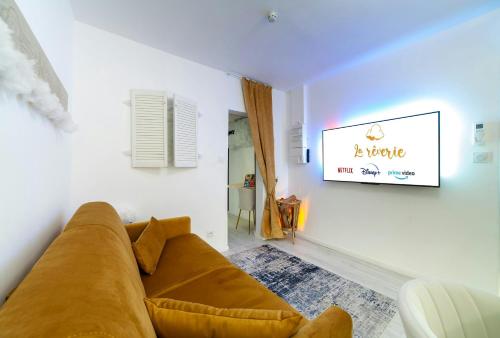 a living room with a couch and a tv on a wall at La Rêverie - Jacuzzi Lounge & Massage in Vierzon