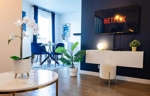 un salon avec une table et une télévision au mur dans l'établissement L'Ecrin Bleu - Proche Paris, à Épinay-sur-Seine