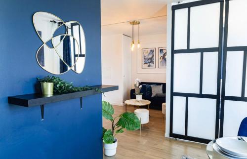 - un salon avec un mur bleu et un miroir dans l'établissement L'Ecrin Bleu - Proche Paris, à Épinay-sur-Seine