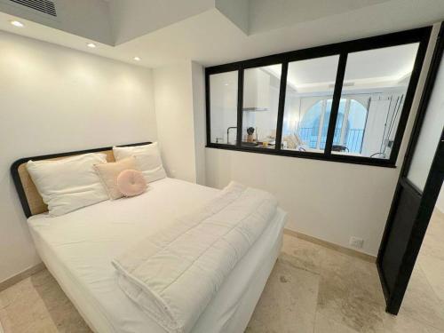 une chambre avec un grand lit blanc avec une fenêtre dans l'établissement ⁂ Magnifique 3P cœur du Vieux Nice, à Nice